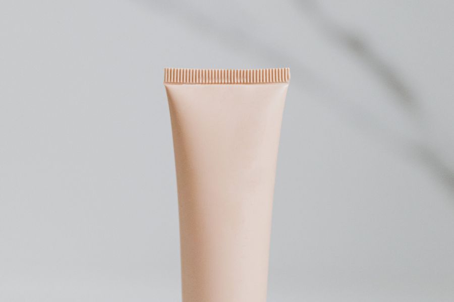 A single cleanser tube standing on a pale marble surface