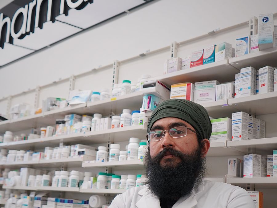 A pharmacist standing in front of a fully stocked dispensary wall